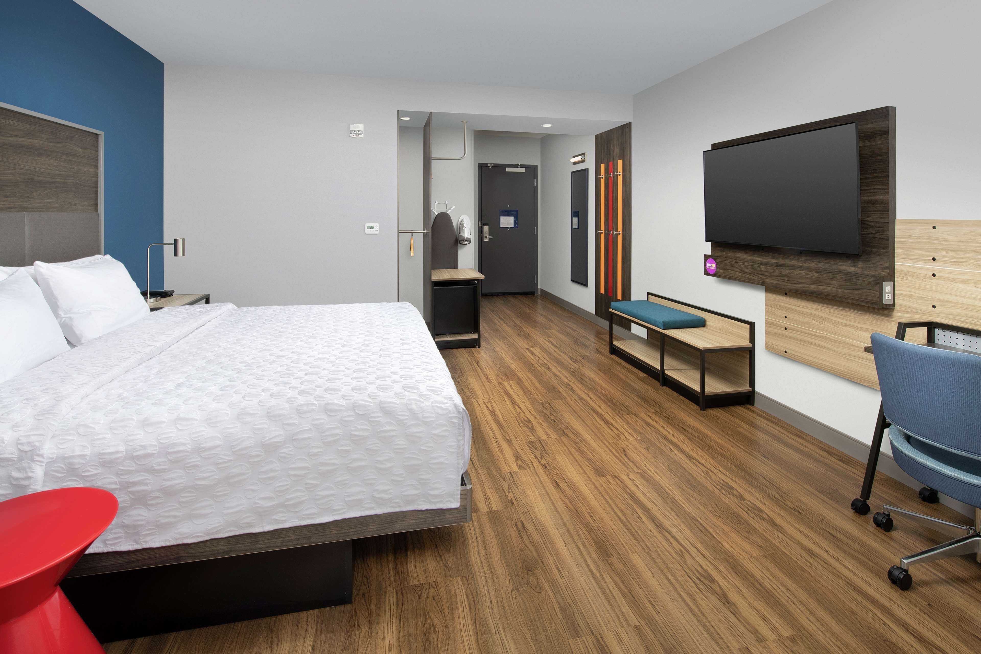 Een moderne hotelkamer met een groot bed, een bureau, een stoel en een flatscreen televisie aan de muur.