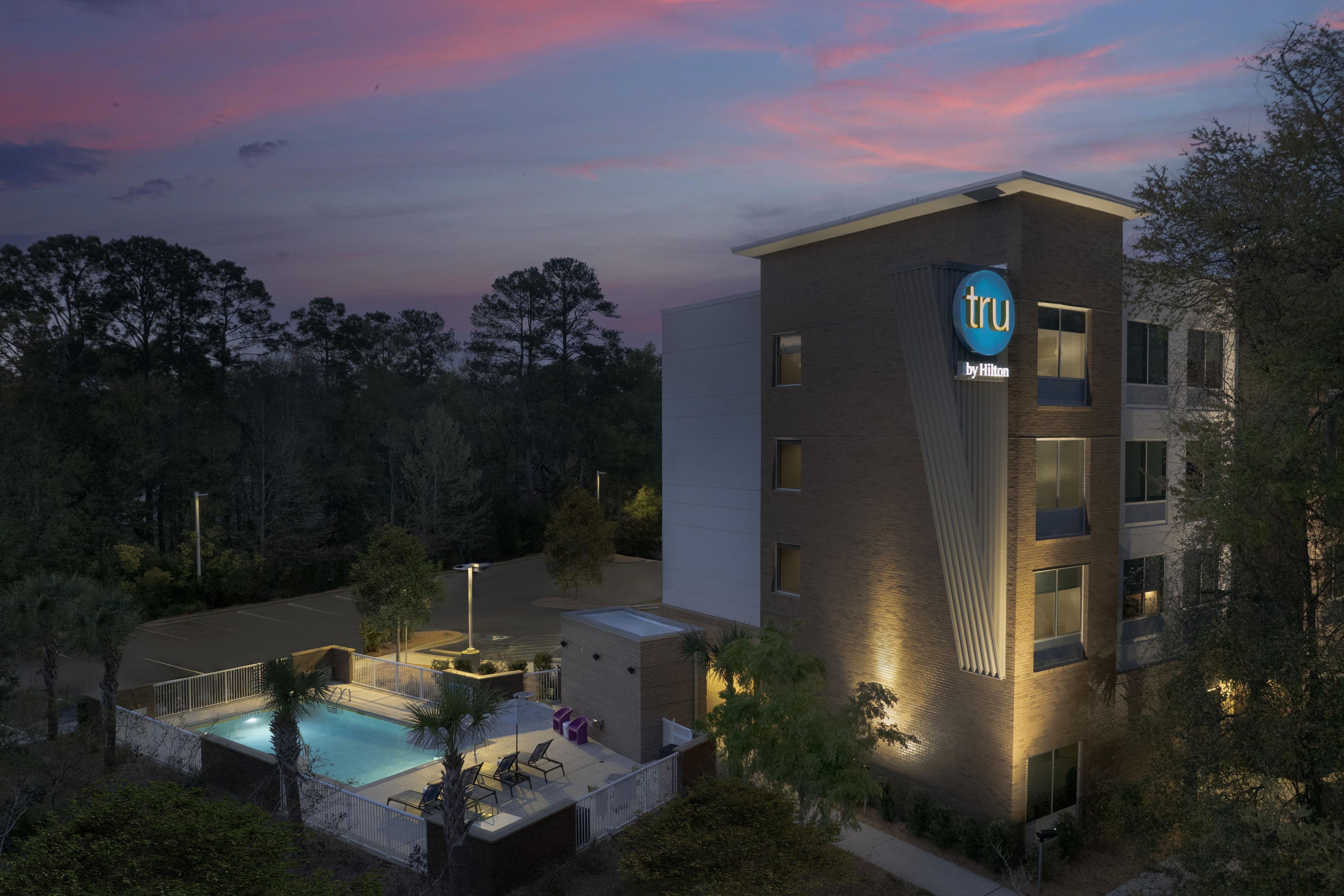 A hotel with a swimming pool, a rooftop terrace, and a sign indicating it's a Hilton hotel.