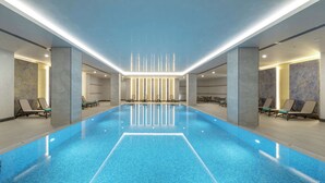 Una amplia piscina interior con diseño moderno, rodeada de sillones de descanso y un interior limpio y minimalista.