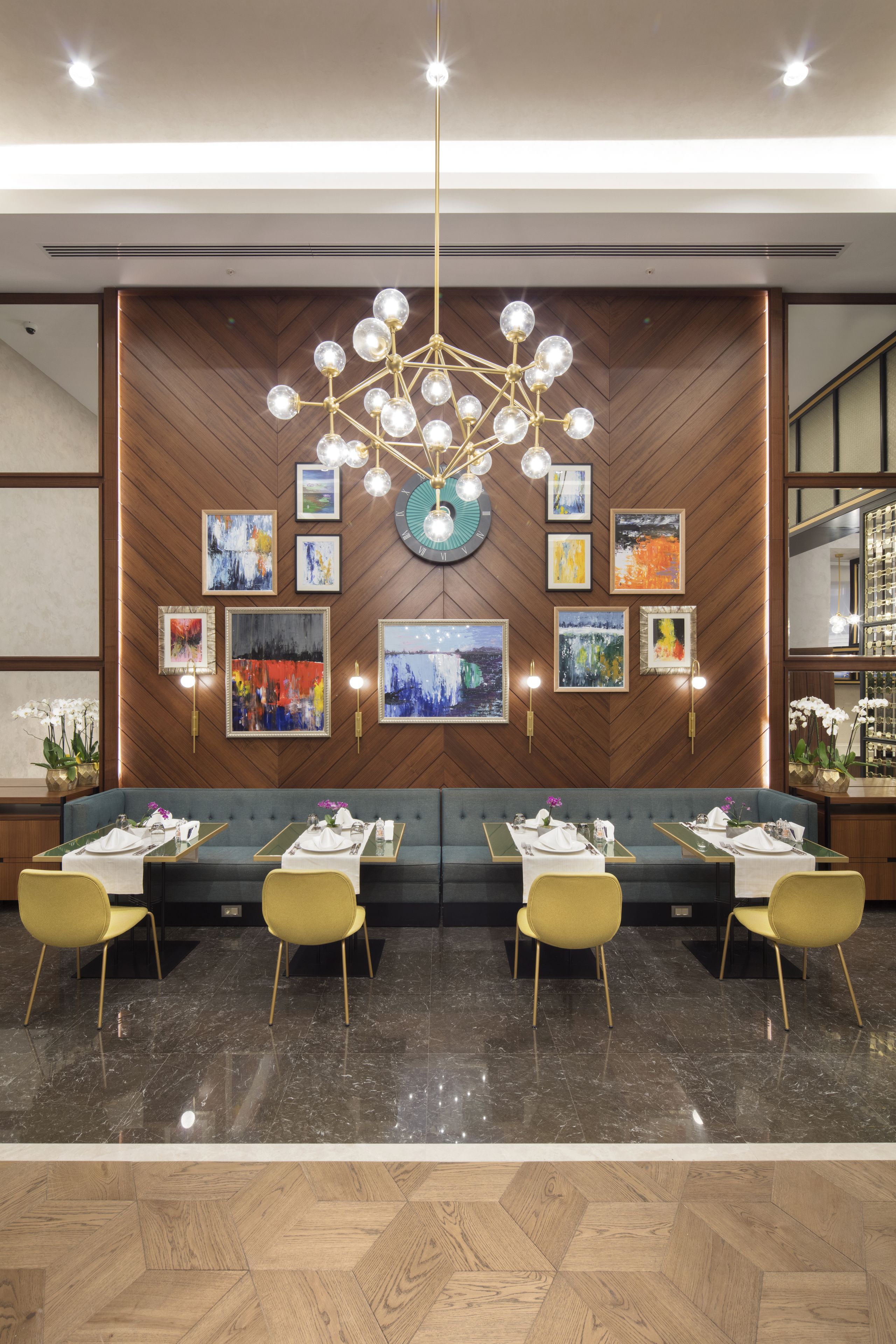 Un comedor moderno con una pared de madera, un candelabro y obras de arte.
