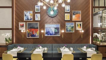 Un comedor moderno con una pared de madera, un candelabro y obras de arte.