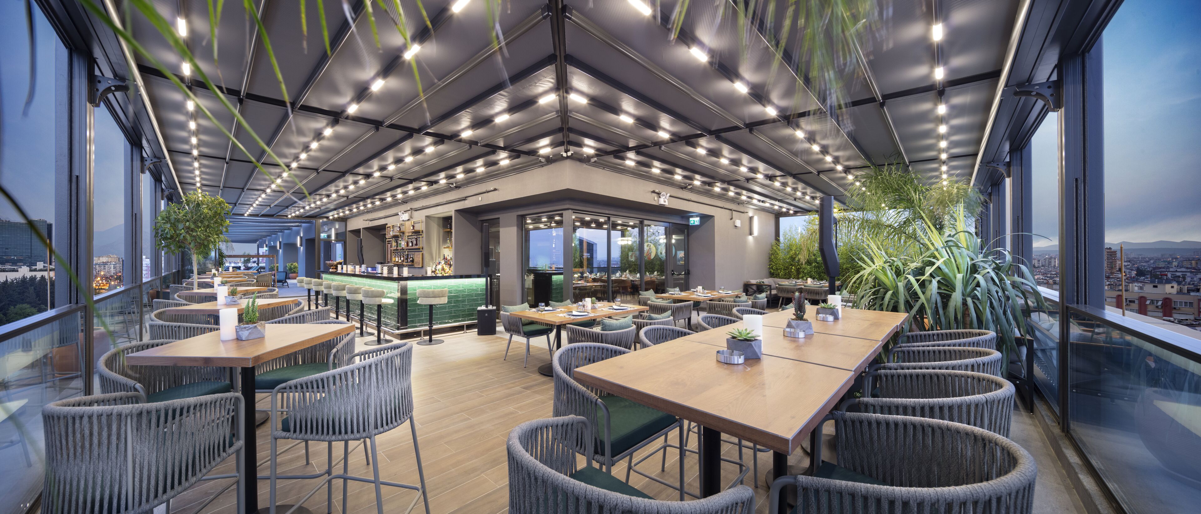 A modern restaurant with high ceilings, exposed ductwork, and a bar area.