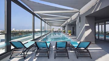 A rooftop pool area with lounge chairs and a clear view of the cityscape.