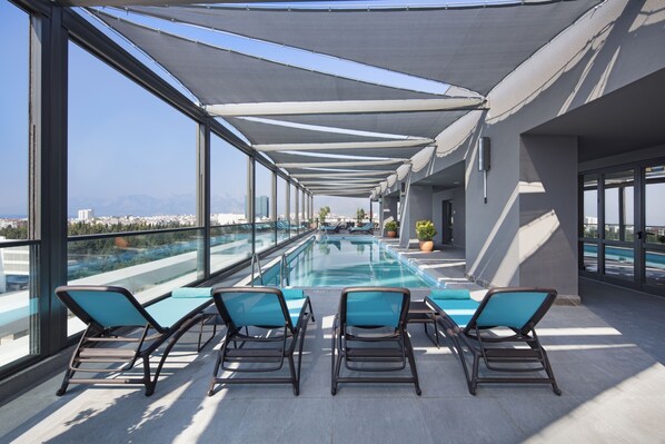 Zona de piscina en la azotea con sillones reclinables y vistas despejadas del paisaje urbano.