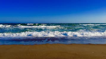 Una playa con olas rompiendo en la orilla bajo un cielo azul despejado.