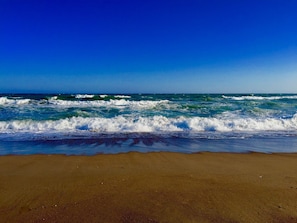 A beach with waves crashing onto the shore under a clear blue sky. - DoubleTree By Hilton Antalya City Centre (Antalya)