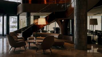A modern lobby with a curved staircase, leather seating, and a large floor lamp.
