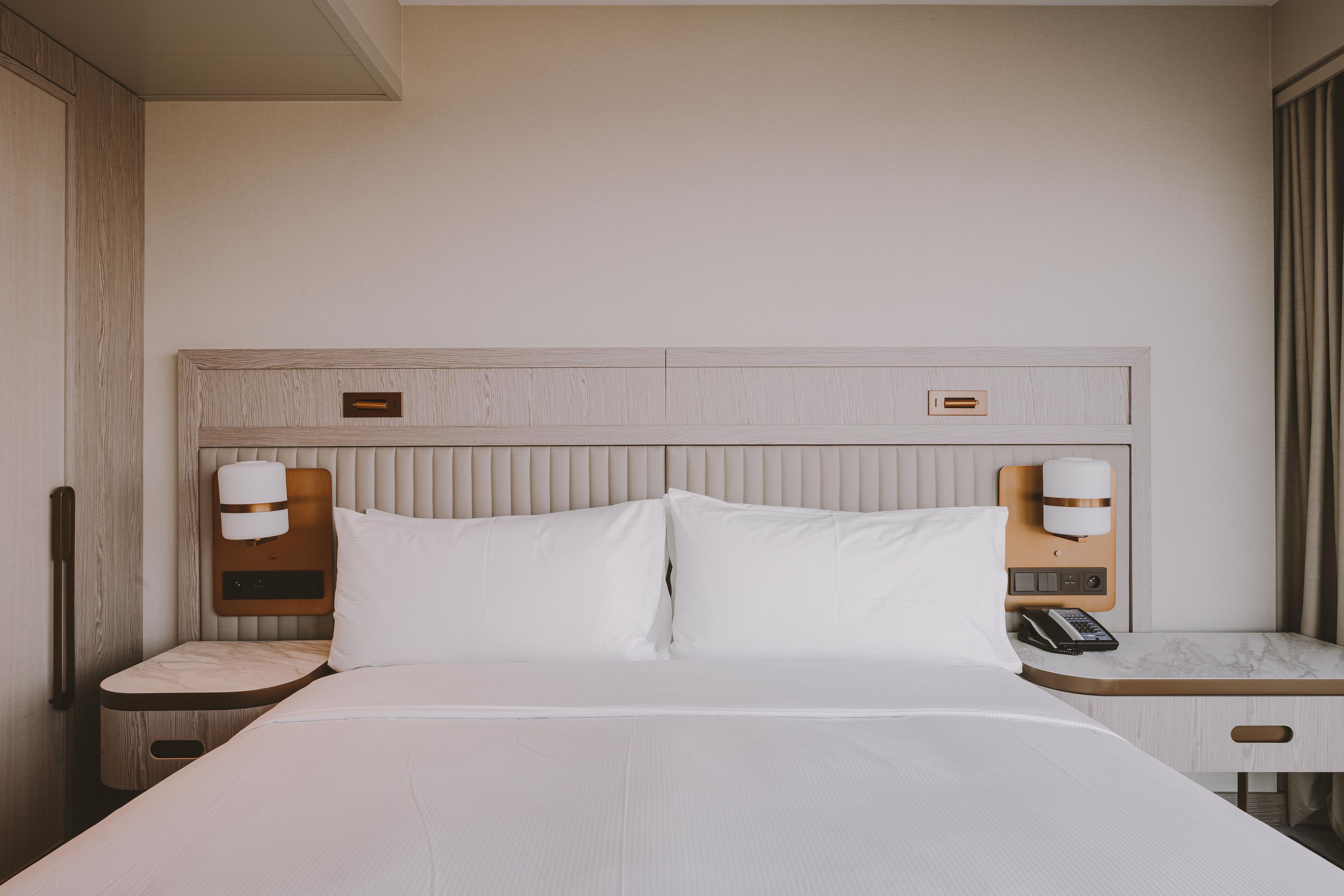 Ein Hotelzimmer mit einem Bett, Nachttischen, einem Telefon und einem kleinen Tischchen.