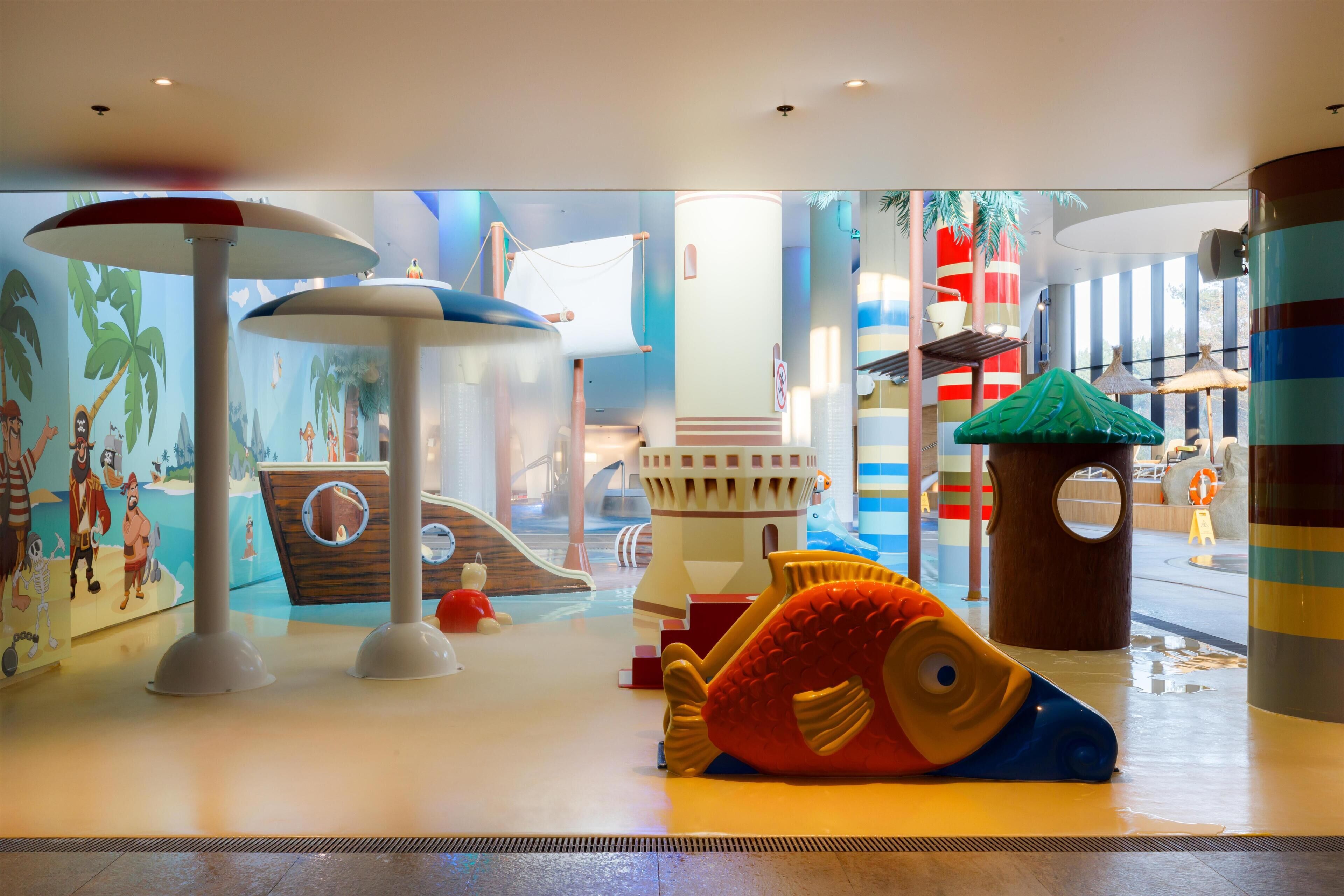 A children's play area with a slide, climbing structures, and a large fish-shaped play sculpture.