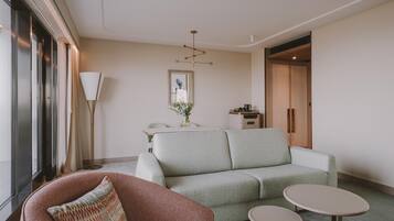 Een moderne woonkamer met een bank, een stoel, een bijzettafeltje en een vloerlamp.