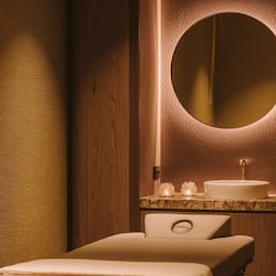Bathroom features a round mirror, white sink, and a towel.