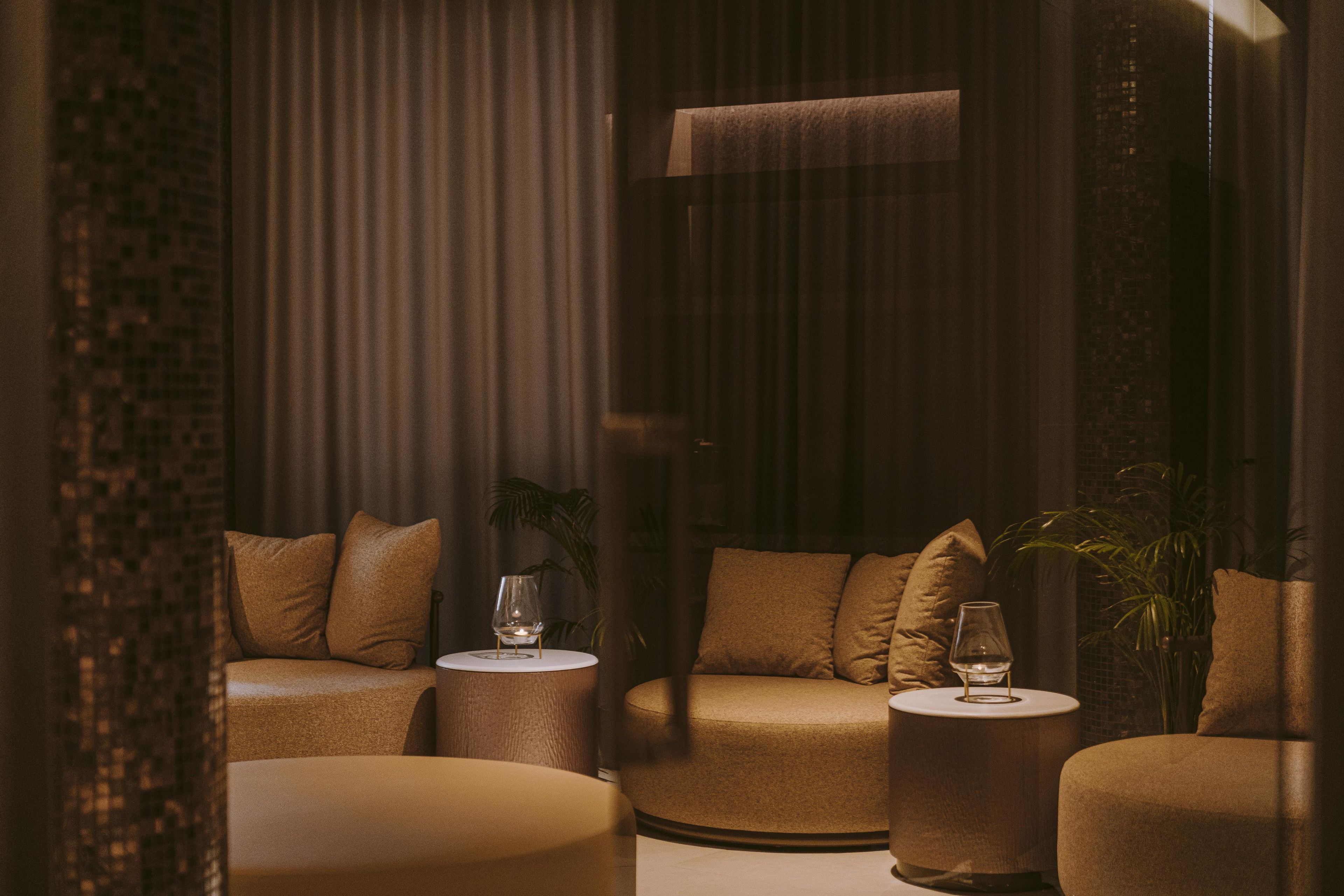 A modern lounge area with sofas, round tables, and a glass display.