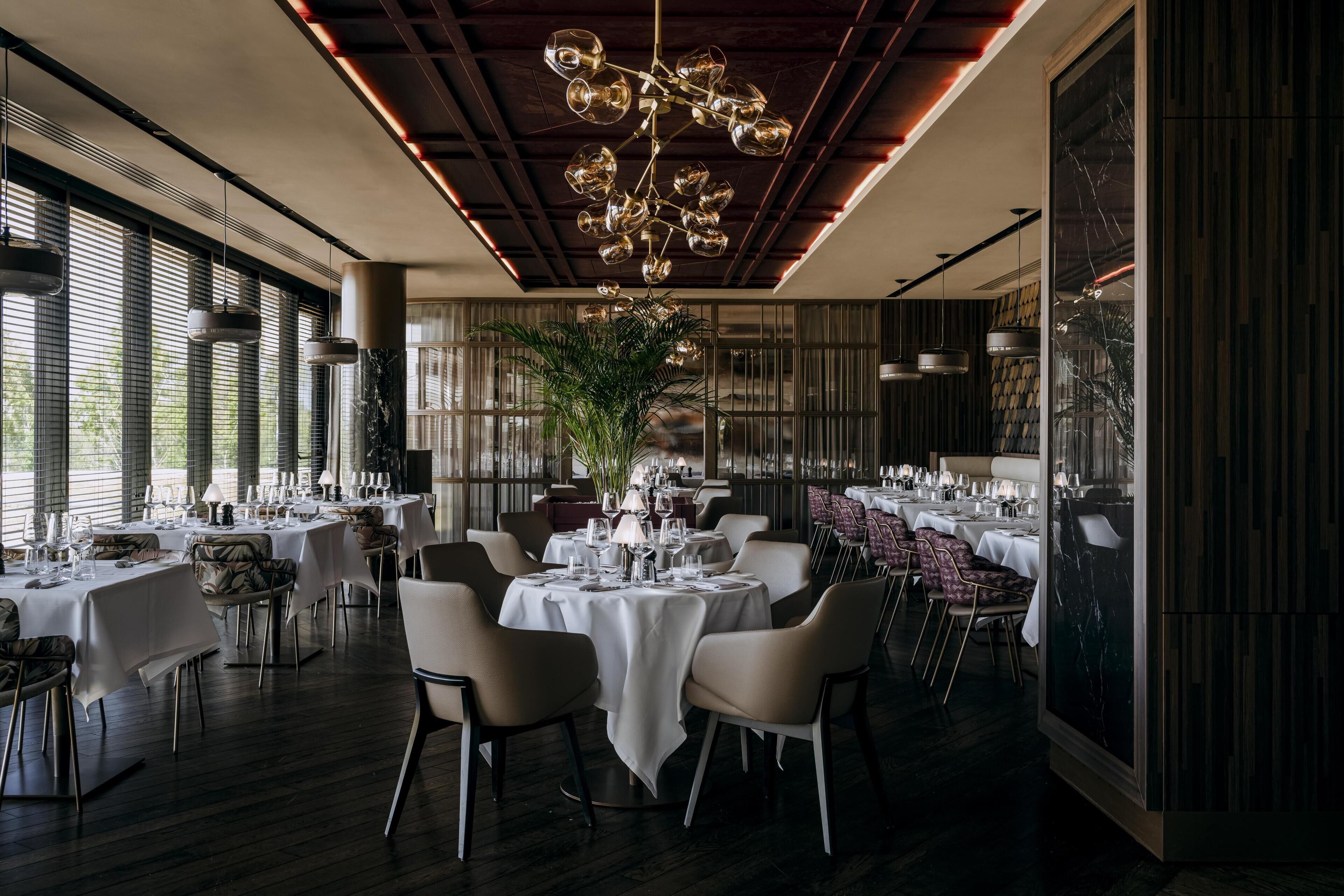 Un restaurant avec des tables et des chaises rondes, ainsi qu’un lustre unique.