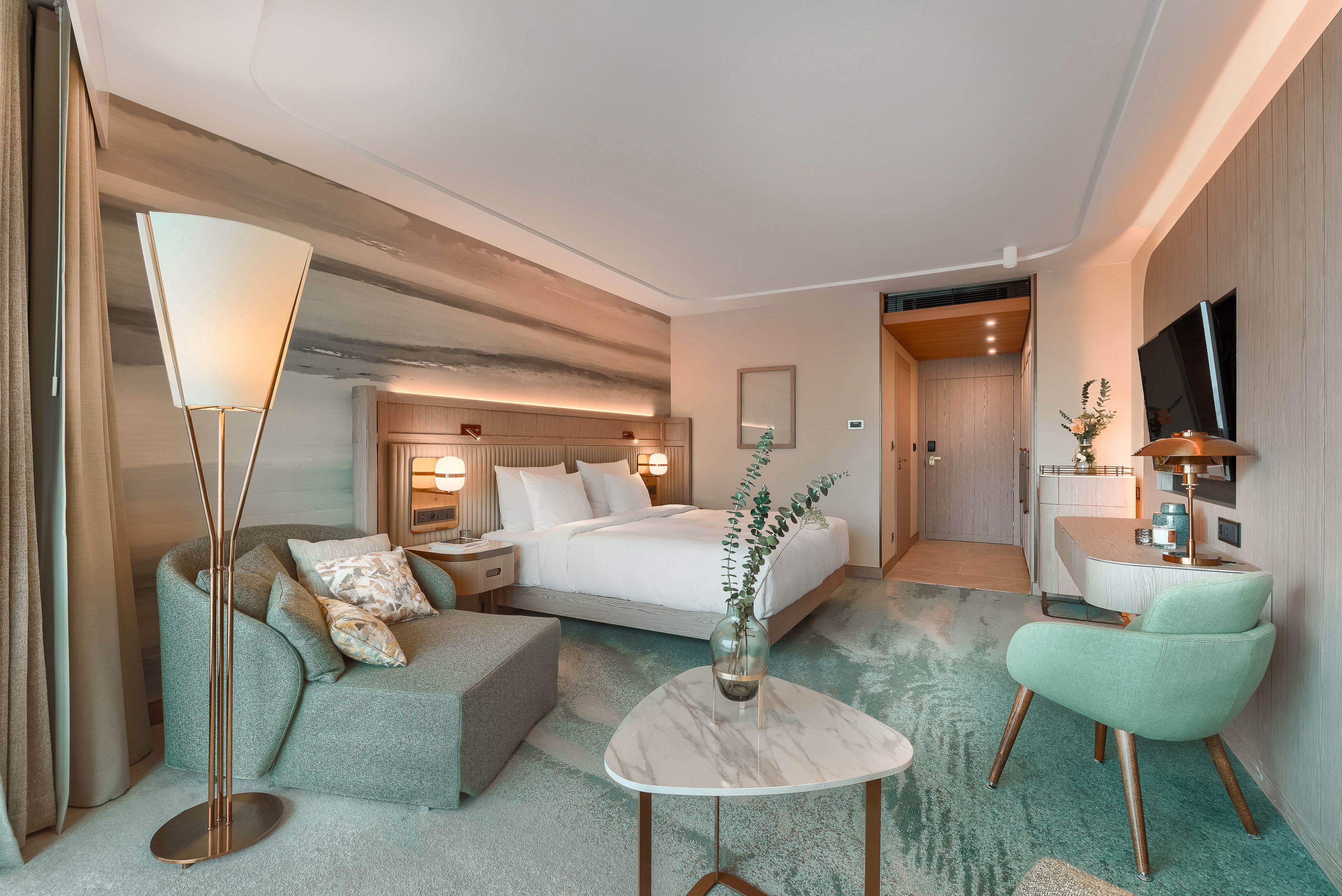 Una habitación de hotel moderna con una cama, un sofá, una mesita de café, un televisor y un escritorio.