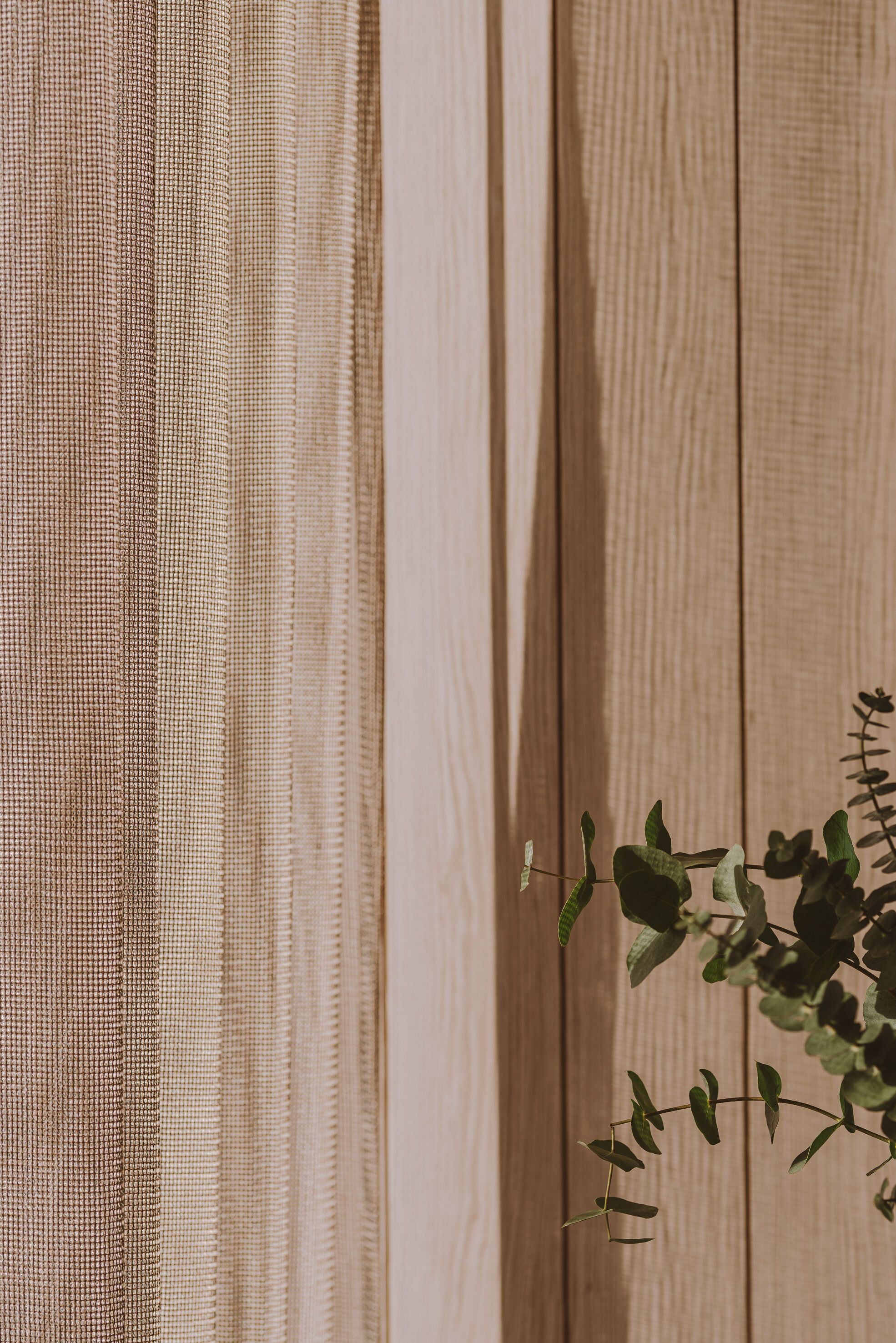 A wooden wall with a textured fabric hanging on it.