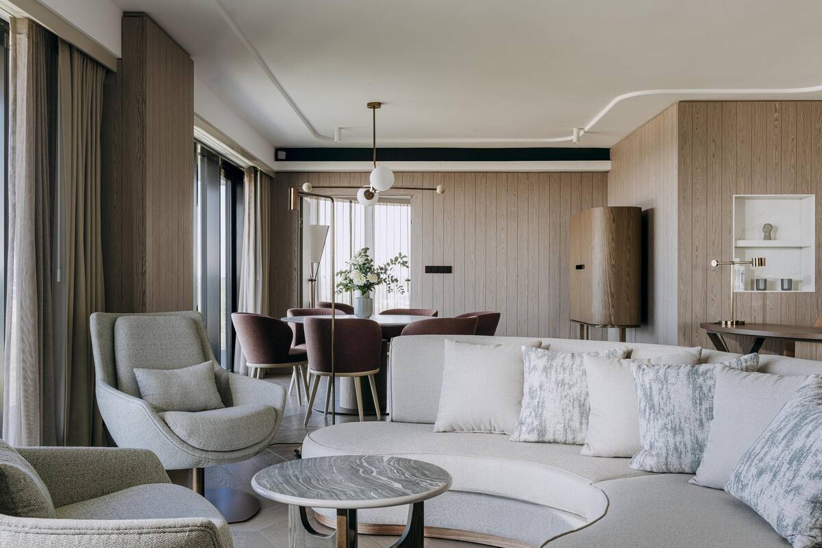 Una sala de estar moderna con un sofá, sillones, una mesa de centro y un comedor con sillas y una mesa.