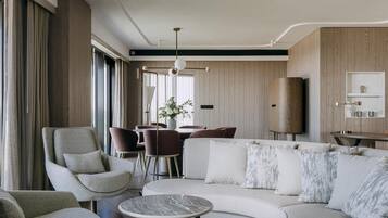 A modern living room with a sofa, armchairs, a coffee table, and a dining area with chairs and a table.