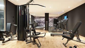 Een moderne sportschool met diverse fitnessapparaten, waaronder krachtapparaten, loopbanden en gewichten.