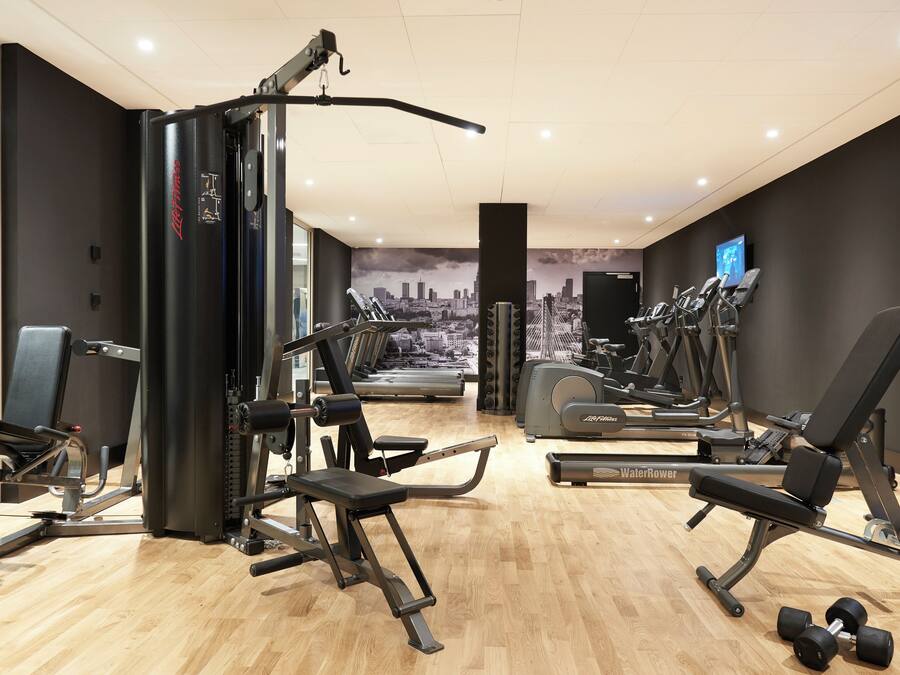 Een moderne sportschool met diverse fitnessapparaten, waaronder krachtapparaten, loopbanden en gewichten.