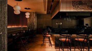 Un área de bar moderna con paneles de madera, una encimera de mármol y varias lámparas colgantes.