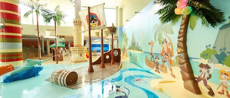A children's play area with a pirate ship, palm trees, and a mural of pirates.