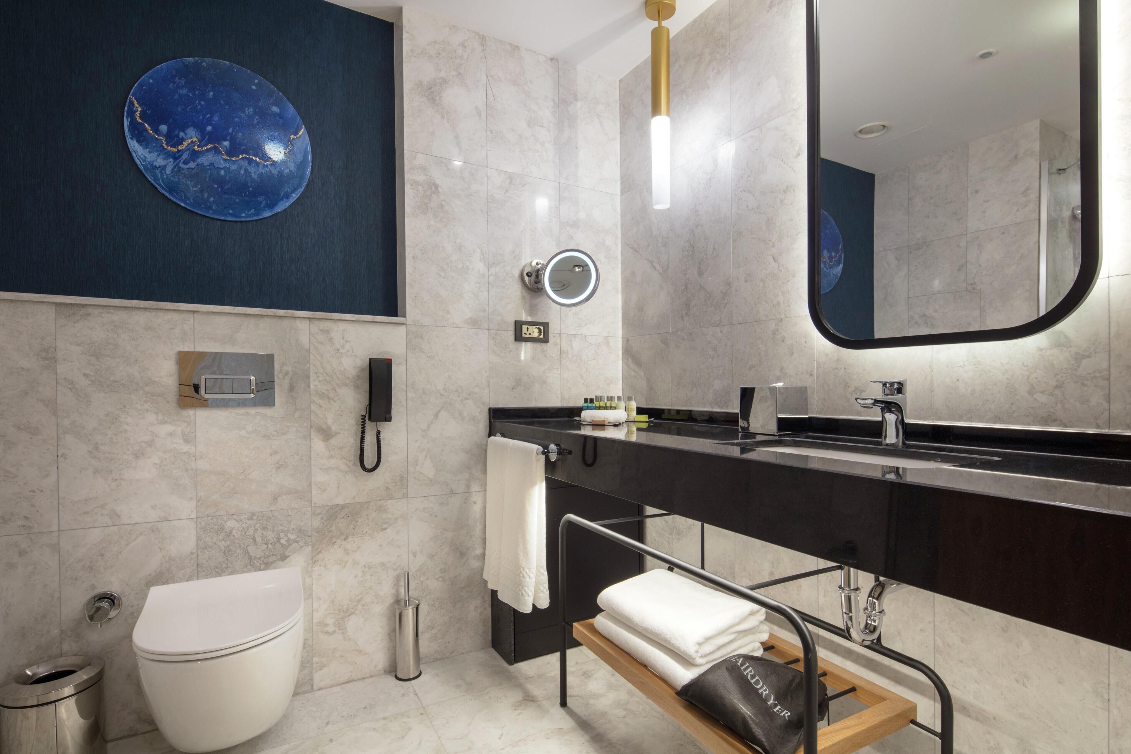 A modern bathroom with a toilet, sink, and mirror.
