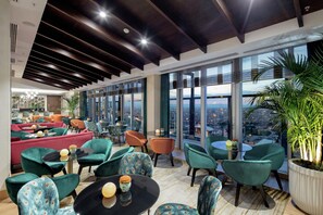 A modern lounge area with seating, a view of the city, and a large potted plant. - DoubleTree by Hilton Afyonkarahisar (Afyonkarahisar)