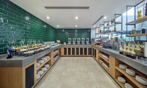 A buffet setup with a green tiled wall, multiple serving stations, and a variety of food and drink options. - DoubleTree by Hilton Afyonkarahisar (Afyonkarahisar)