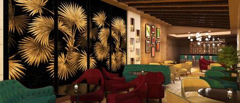 Un interior moderno con una pared de hojas de palma doradas, sillones tapizados en rojo y verde, y una zona de bar con candelabro.