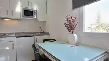 Una cocina moderna con armarios blancos, microondas integrado y un comedor con mesa y sillas.