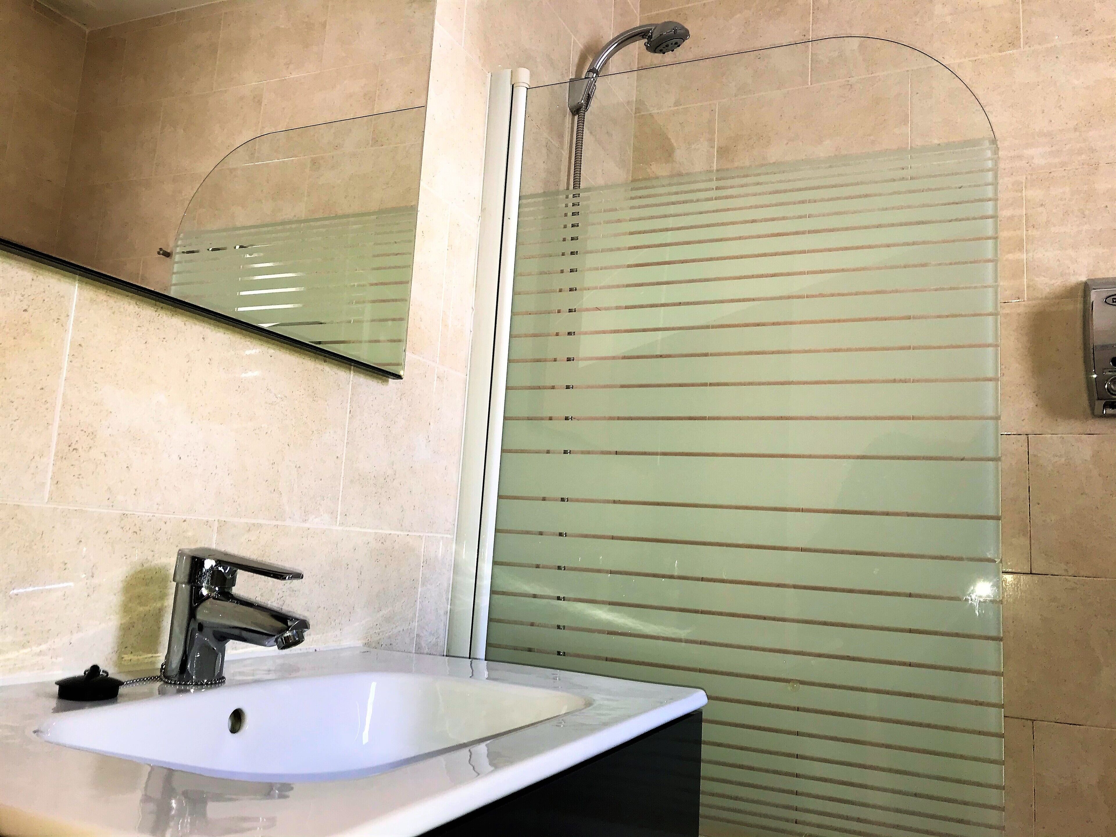 A bathroom with a white sink, a mirror, and a shower enclosure.