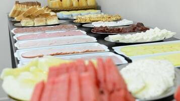 A buffet with various food items including meats, cheeses, and pastries.