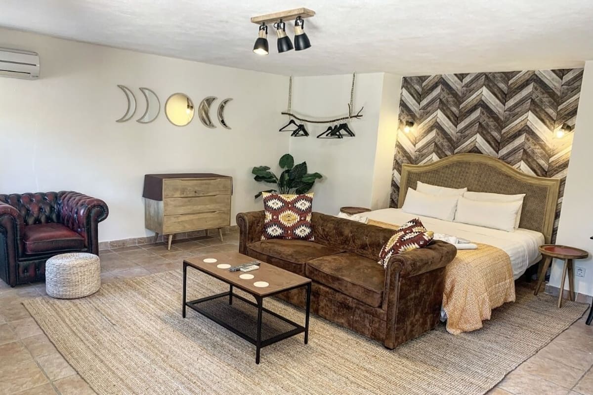 A cozy room with a bed, a sofa, a coffee table, and a dresser.