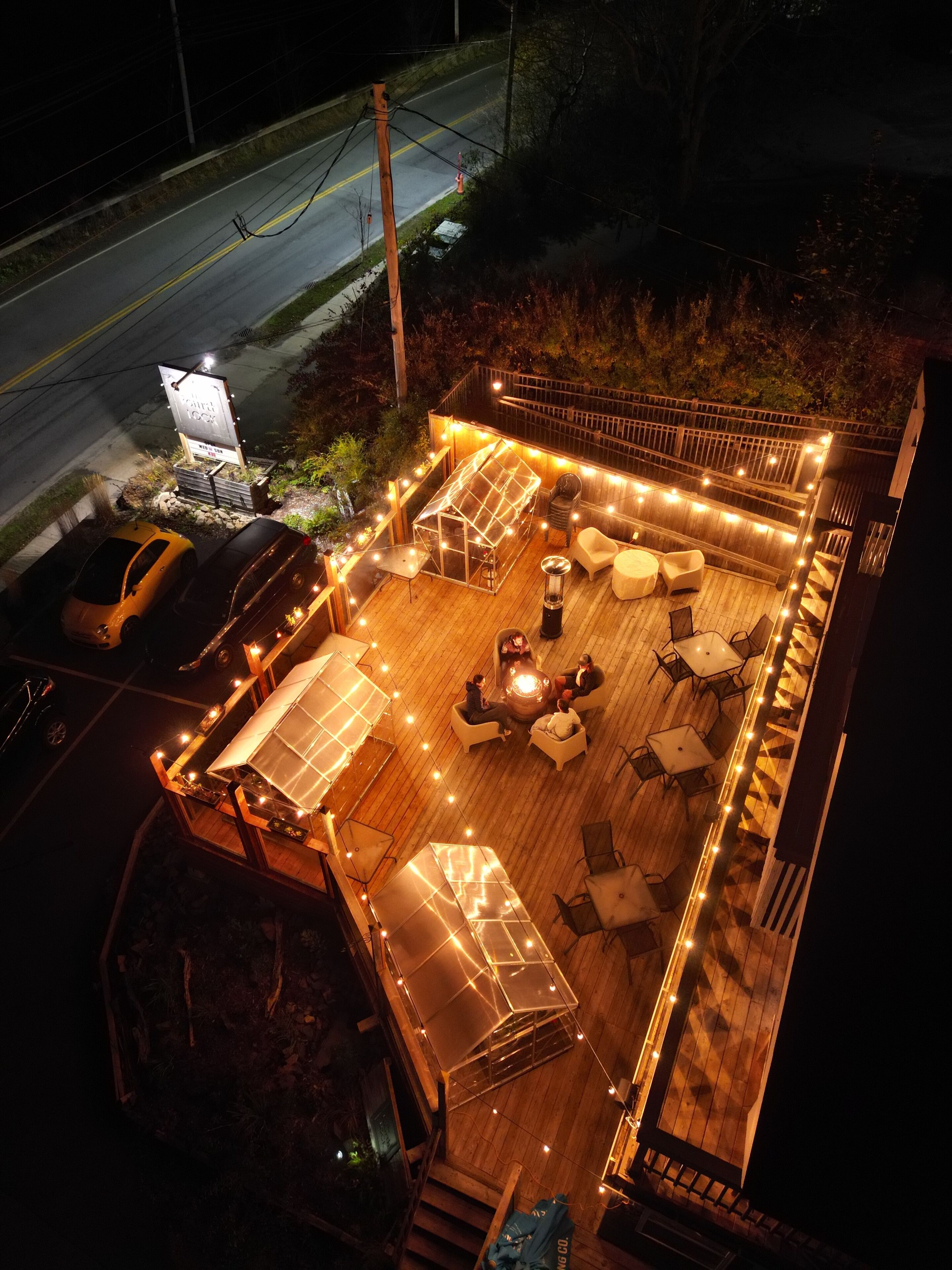 Une terrasse extérieure avec un foyer, des sièges et des guirlandes lumineuses.
