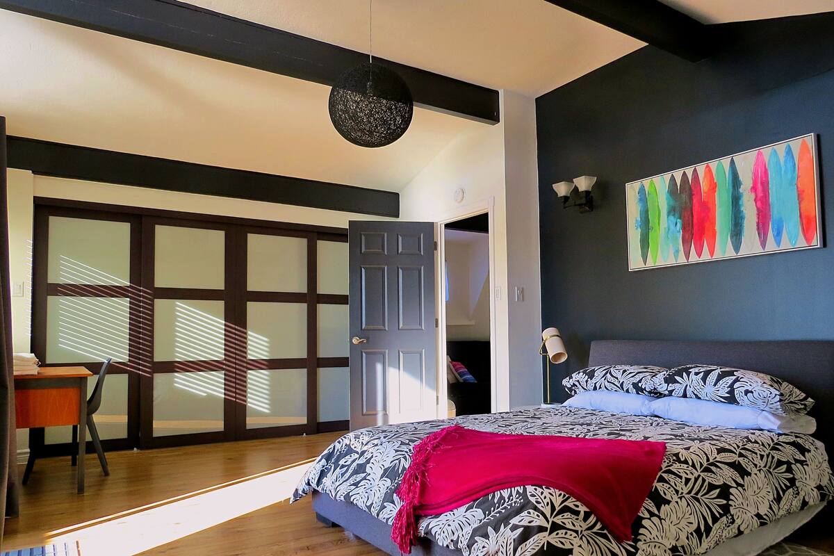 A bedroom with a bed, a desk, and a chair.