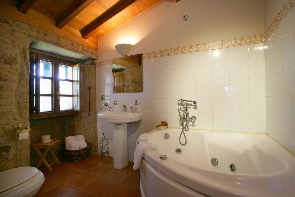 A bathroom with a large bathtub, a sink, and a window with curtains.