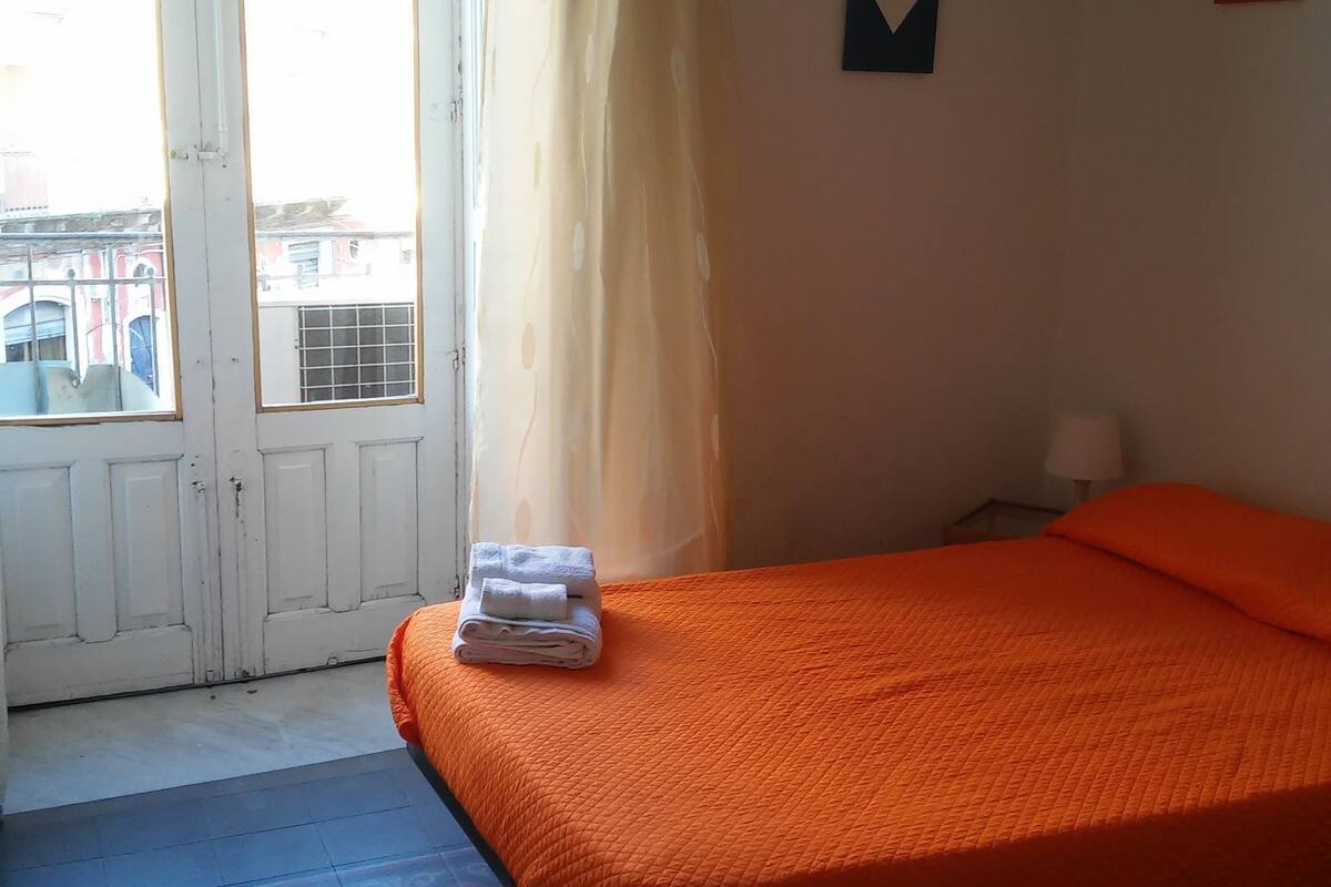 Ein Zimmer mit Bett, einem Vorhangfenster, einer Klimaanlage und einem gemusterten Teppich.