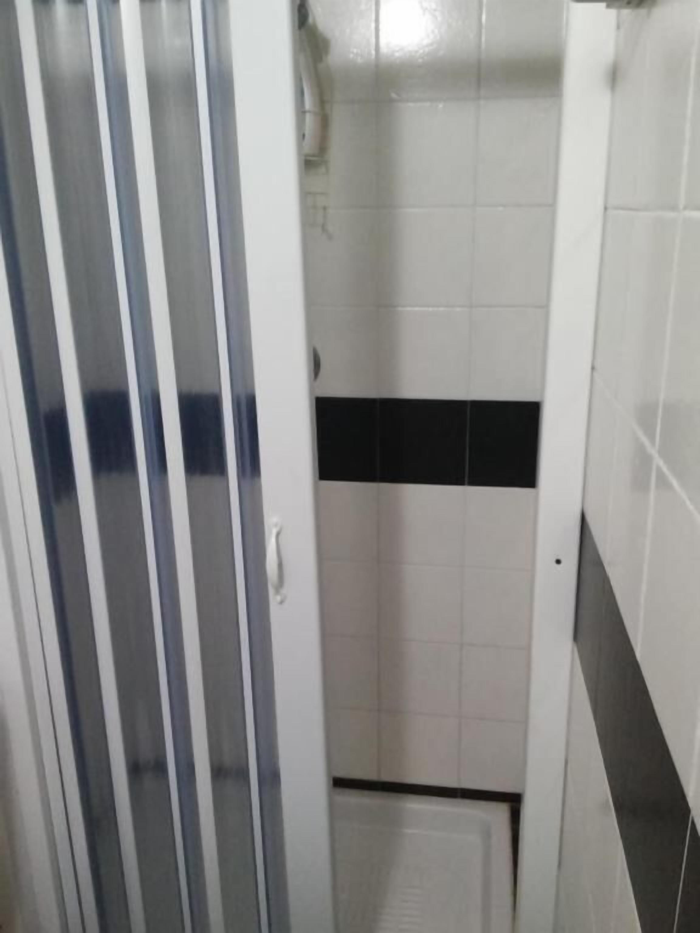 A bathroom with a shower, white and black tiled walls, and a glass door.