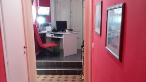 A narrow hallway with a checkered floor leading to a room with a desk, chair, and a computer. - A Due Passi B&B (Catania)