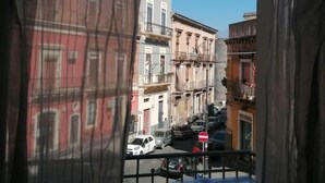 A view from a balcony with a clear blue sky, featuring a street with parked cars and buildings with balconies. - A Due Passi B&B (Catania)