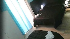 A room with a bed, a chair, and a small table. There is a window with curtains, a wall-mounted air conditioner, and a mirror. - A Due Passi B&B (Catania)