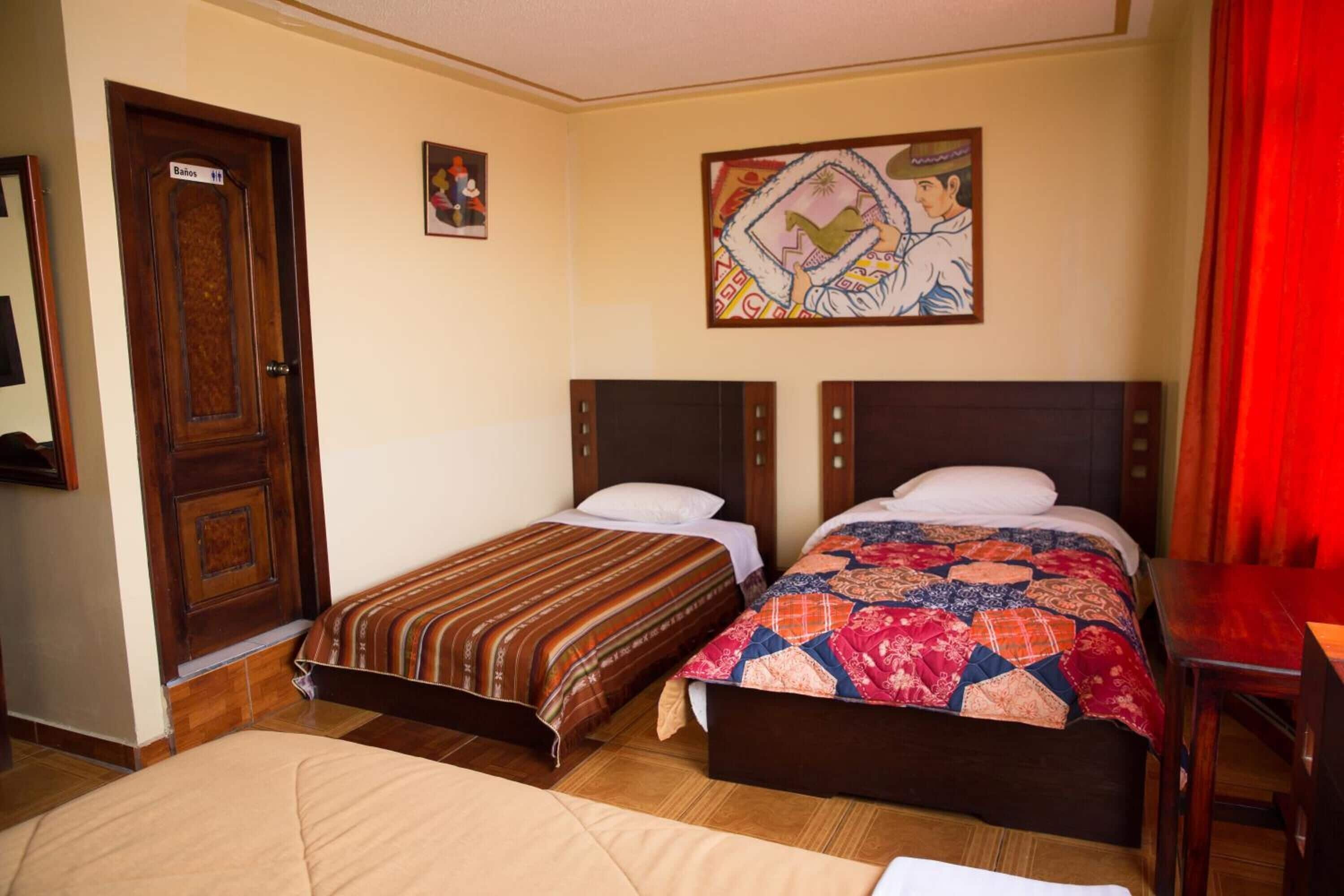 A hotel room with two beds, a wooden door, and a painting on the wall.