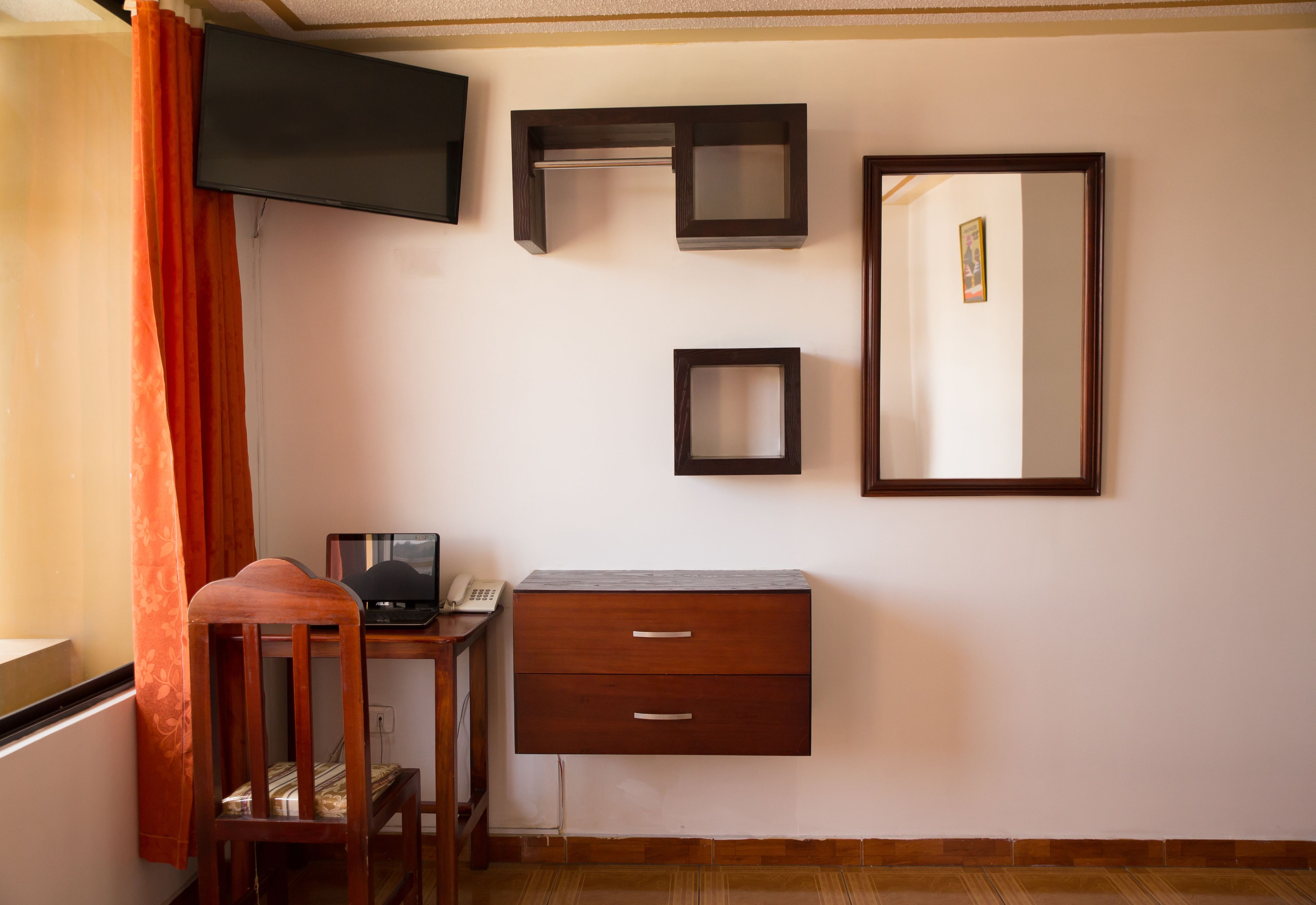 Una habitación con escritorio, silla y un espejo grande.