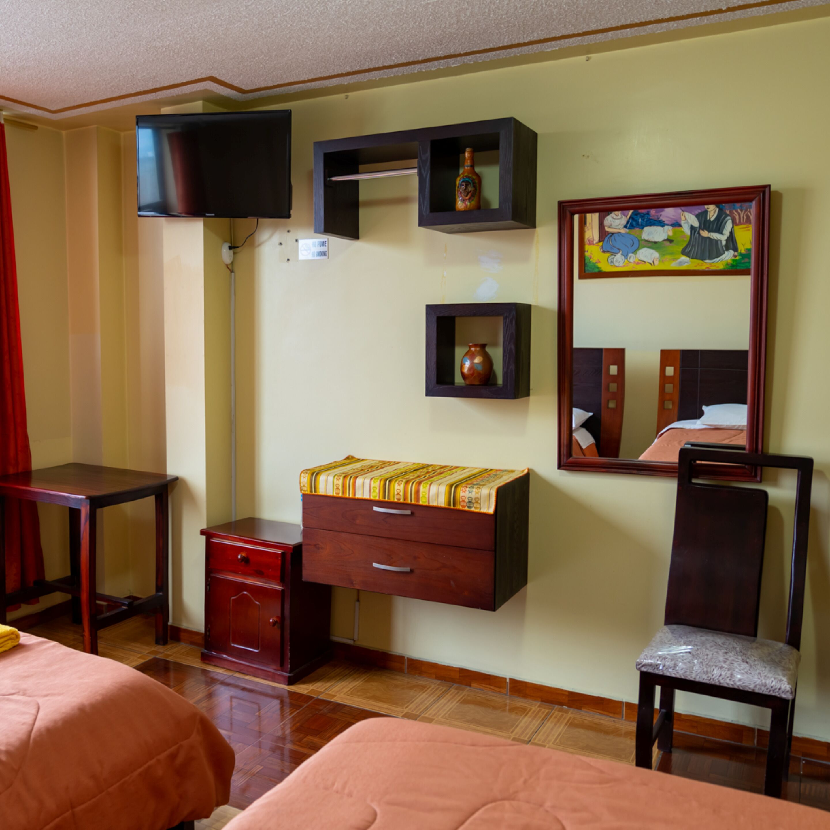 Une chambre d’hôtel avec un lit, un bureau, une chaise, un téléviseur fixé au mur et un tableau.