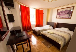 Ein Hotelzimmer mit zwei Betten, einem Schreibtisch, einem Fernseher und einem Bild an der Wand.