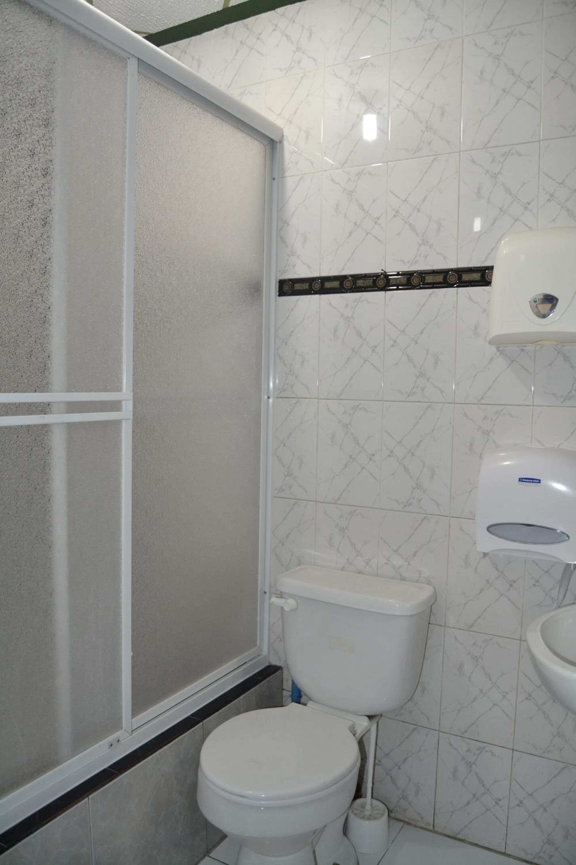 A bathroom with a toilet, a shower enclosure, and a sink.