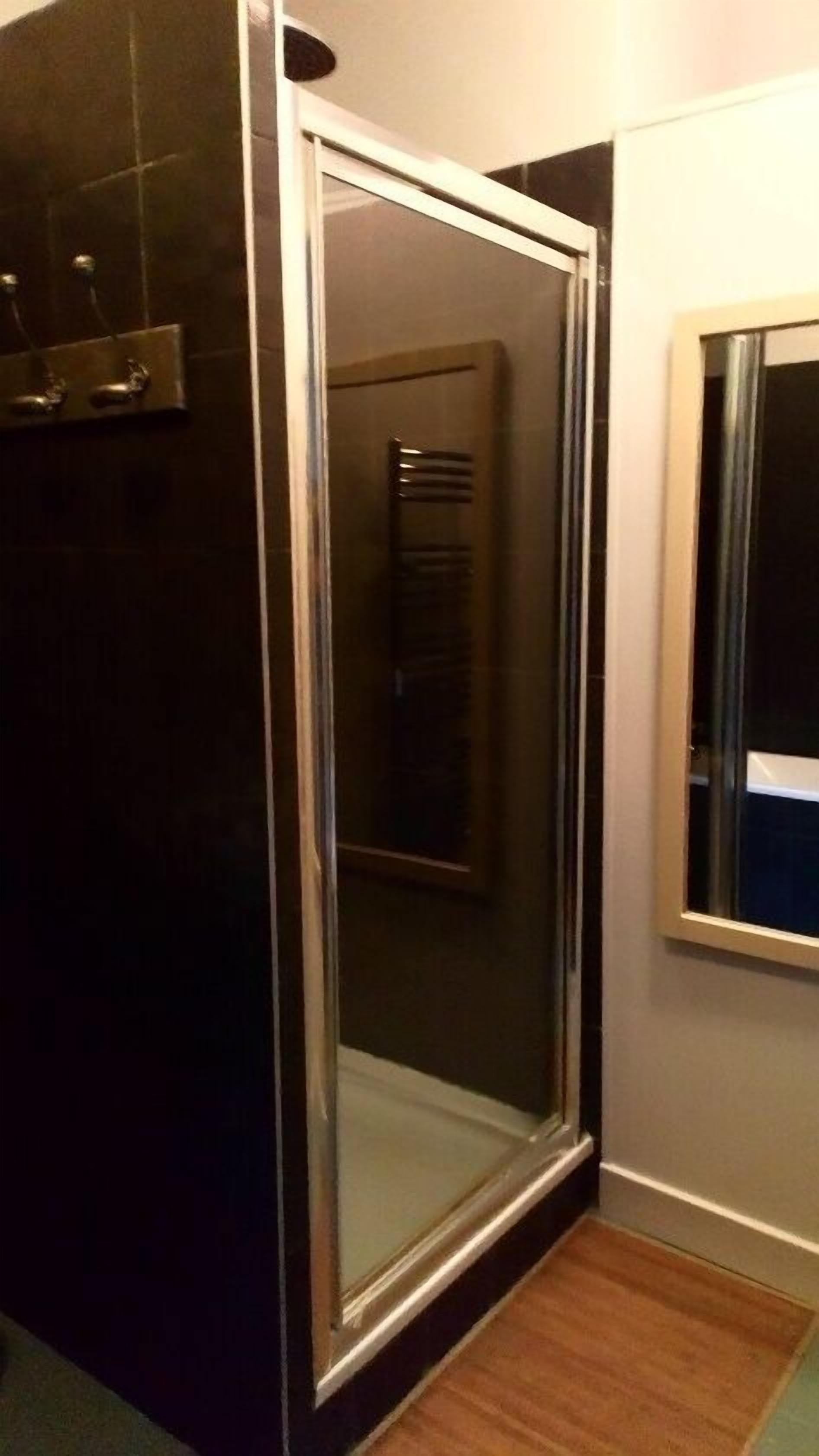 A bathroom with a glass shower enclosure, a towel rack, and a mirror.