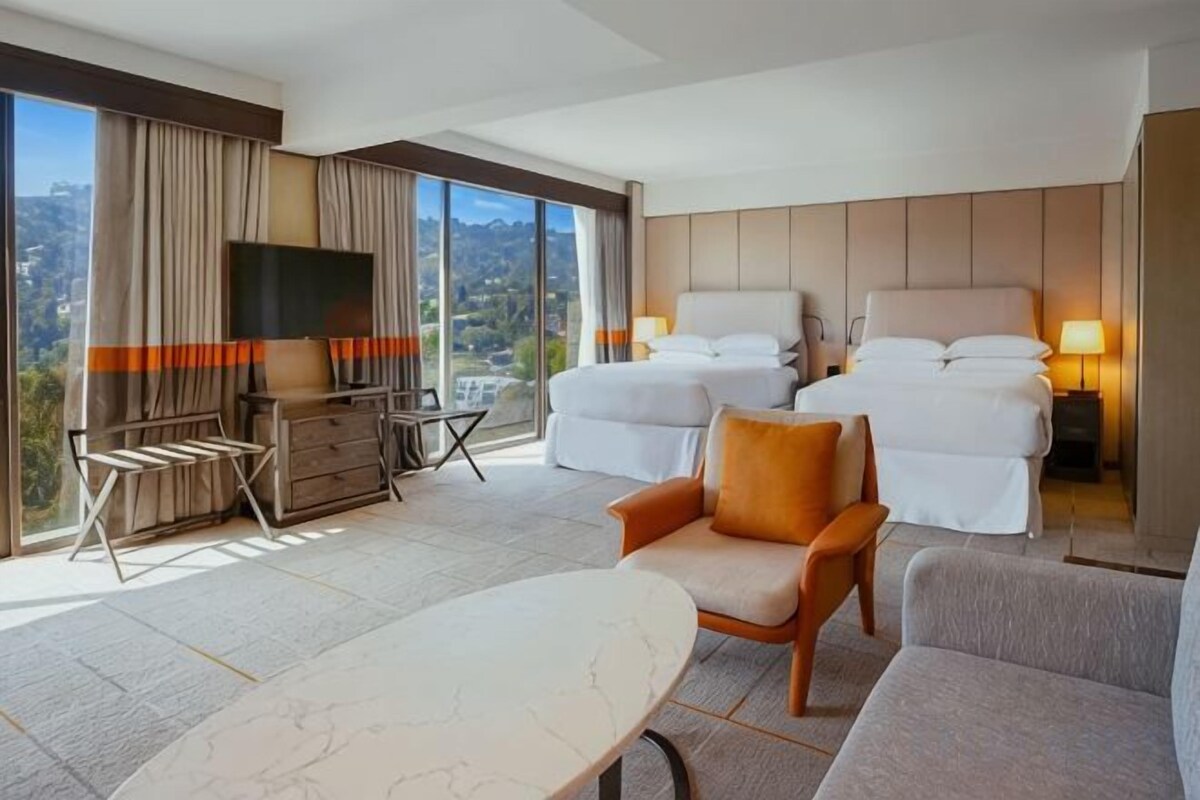 Habitació d'hotel amb llit, televisió, escriptori i vistes a la ciutat.