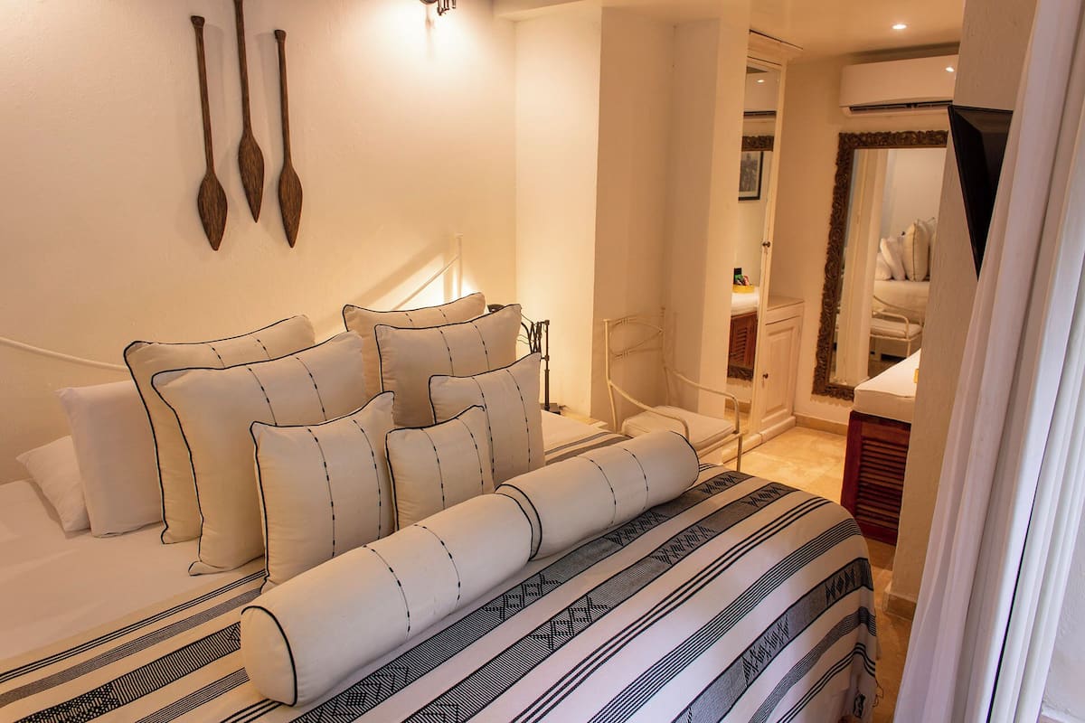 A neatly arranged bedroom with a bed, pillows, and a bedside table.