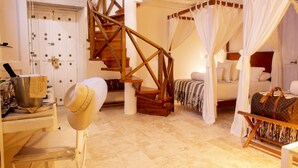 A bedroom with a wooden staircase, a bed with white curtains, and a suitcase on the floor. - Leones de Alba Hotel Boutique (Cartagena)